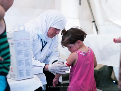 An image of a nurse placing an armband on a small child in the mobile health clinic