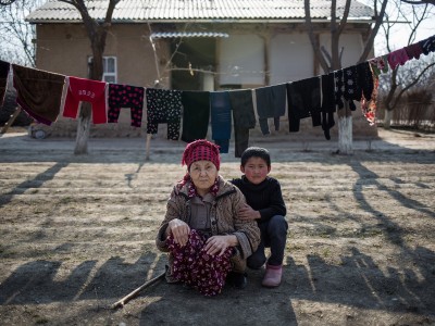 A grandmother and her grandson sit outside their home in Tajikistan