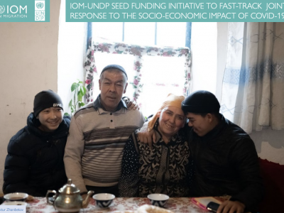 An image of a Kyrgyz family seated together around a table and smiling