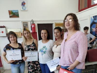 five women are smiling to the camera with three holding a certificate