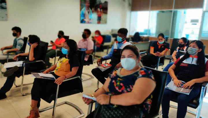 A group of people wearing masks and sitting in a meeting room