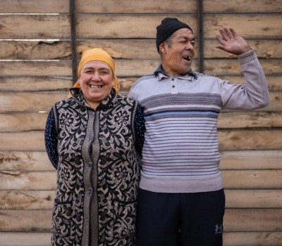 An image of a Kyrgyz man and woman smiling together outside their home